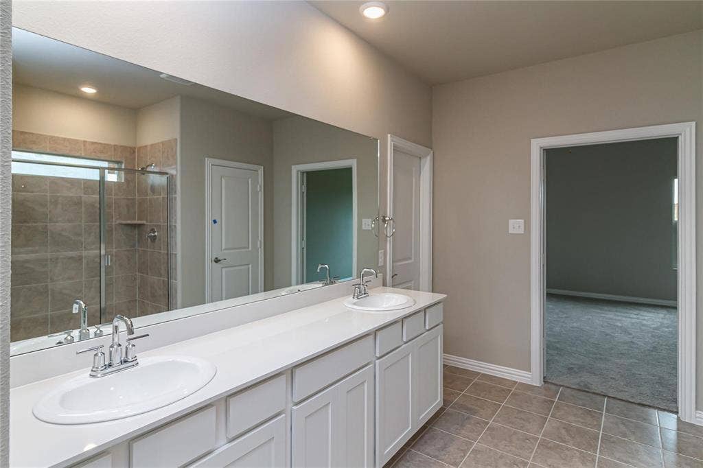 448 Ella Lane, Fate, TX 75087 Dual vanity with white cabinetry, integrated sinks, chrome faucets, and an expansive wall-mounted mirror