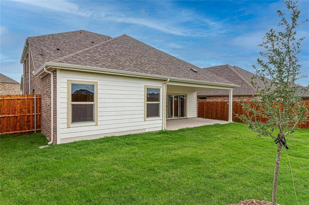 448 Ella Lane, Fate, TX 75087 Expansive backyard featuring a covered patio, manicured lawn, and privacy fencing