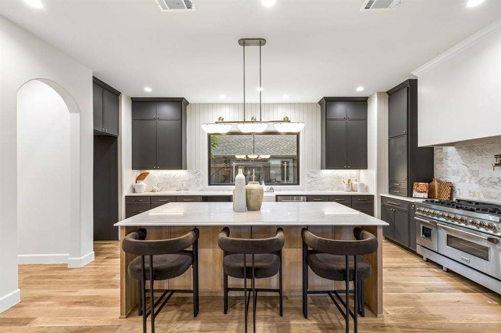 16834 Mossy Oak Drive, Dallas, TX 75248 Chef's kitchen with large center island, a picturesque window, designer lighting and custom cabinetry