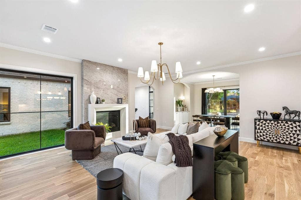 16834 Mossy Oak Drive, Dallas, TX 75248 Living room with fireplace flanked by Taj Mahal tile with a view into the formal dining space