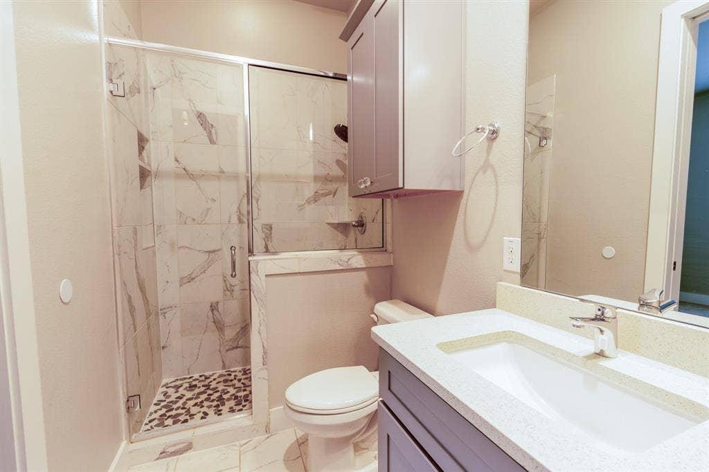 2514 Vintage Street, Farmers Branch, TX 75234 Contemporary en-suite 1st floor bathroom featuring a walk-in shower with a glass enclosure, large format tile, and a pebble floor