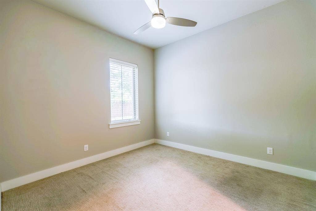 2514 Vintage Street, Farmers Branch, TX 75234 Neutral-toned room featuring a single window with blinds, a ceiling fan with integrated lighting, and light-colored carpeting