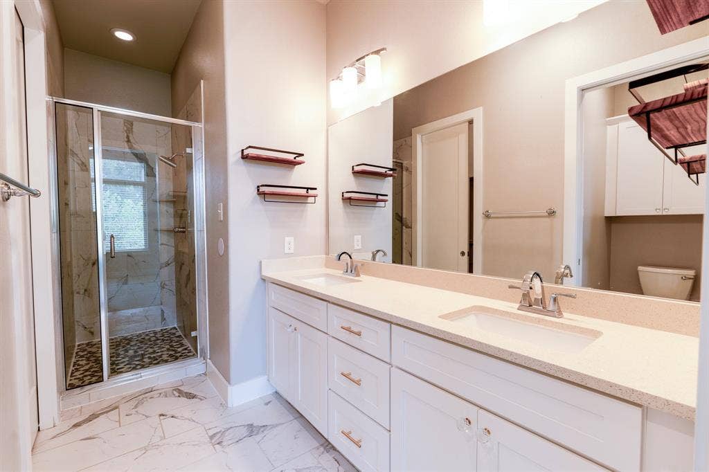 2514 Vintage Street, Farmers Branch, TX 75234 En-suite primary bathroom: Dual vanity with light-toned quartz countertop, integrated double sinks, and polished chrome fixtures