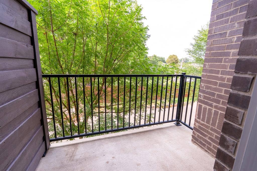 2514 Vintage Street, Farmers Branch, TX 75234 2nd floor outdoor balcony featuring concrete flooring, black metal railing, and a brick exterior wall