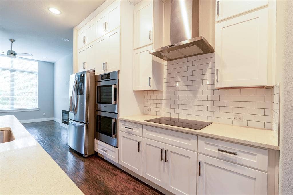 2514 Vintage Street, Farmers Branch, TX 75234 Modern kitchen featuring white shaker cabinetry, stainless steel appliances, a subway tile backsplash, and light-toned quartz countertops