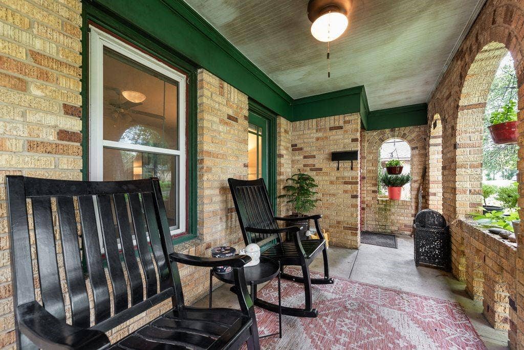 Brick-clad porch featuring arched openings, a ceiling-mounted light fixture, and a solid entry door with sidelight