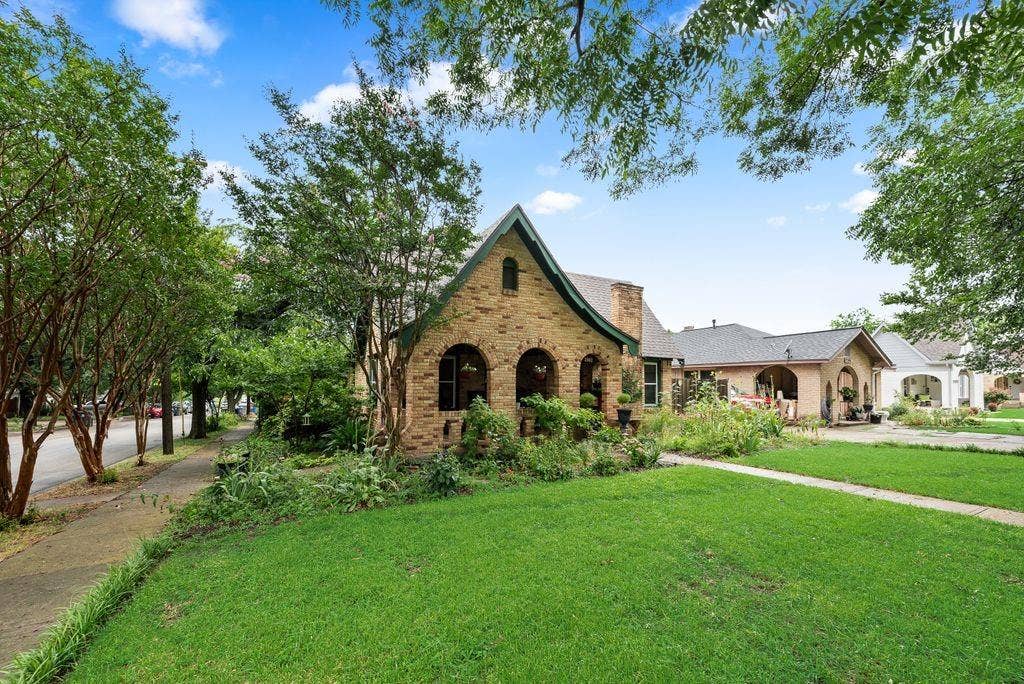 Brick exterior with arch details, gabled roofline, and established landscaping