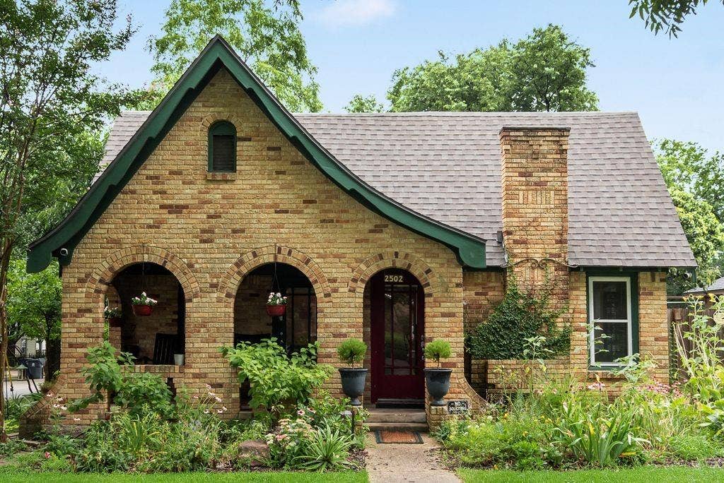 Brick facade residence featuring a prominent chimney and a dark green trim
