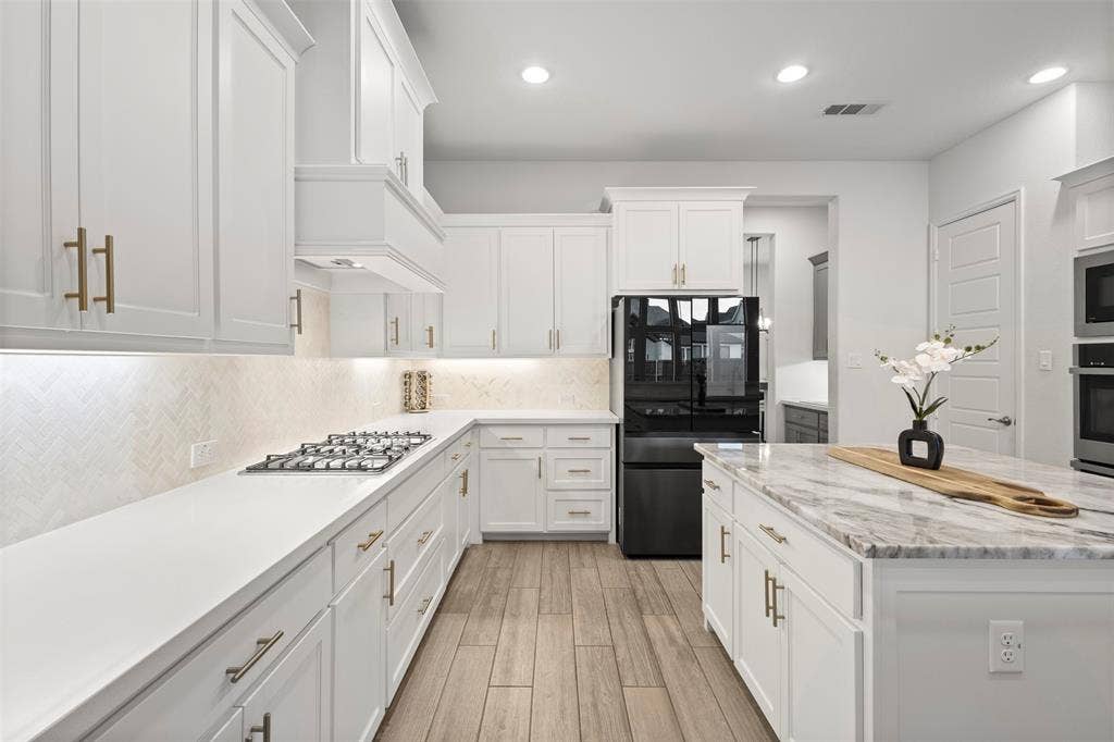 2837 Midlake Drive, Midlothian, TX 76065 Modern kitchen featuring white cabinetry with gold-tone hardware, white countertops, and a herringbone-patterned tile backsplash