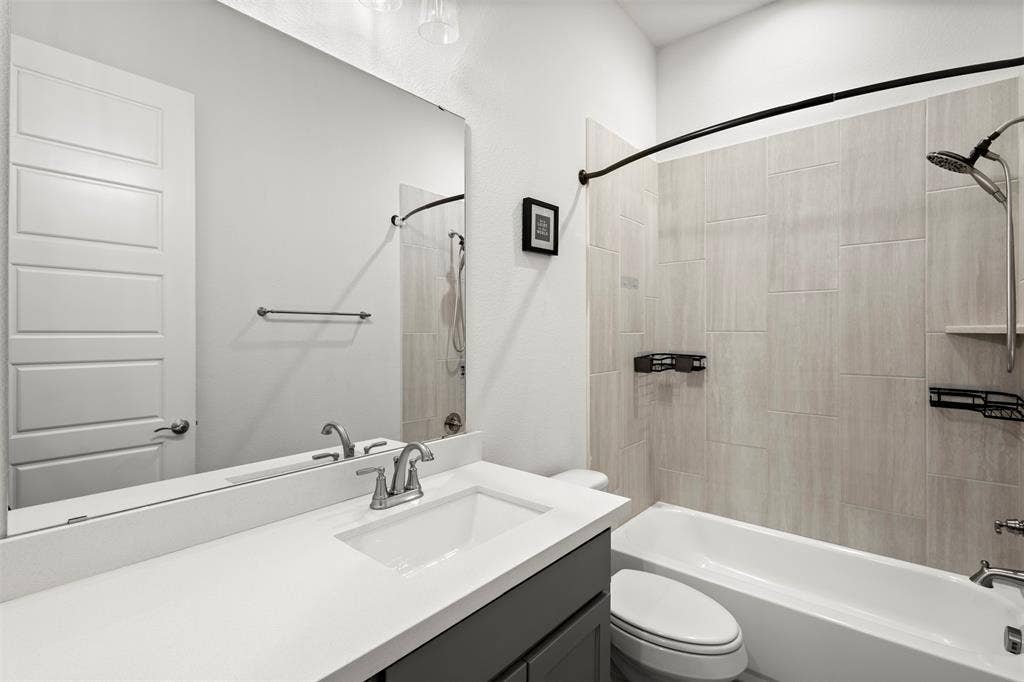 2837 Midlake Drive, Midlothian, TX 76065 Bathroom featuring a white bathtub with a tiled surround, a contemporary vanity with a white countertop and integrated sink, and a large wall-mounted mirror