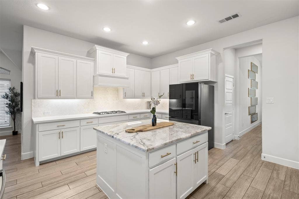 2837 Midlake Drive, Midlothian, TX 76065 Kitchen featuring a central island with a light-toned countertop, white cabinetry with gold-finish hardware, recessed lighting, wood-finish flooring, and a stainless steel appliance