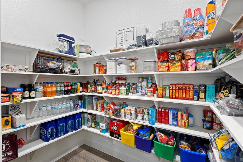 2837 Midlake Drive, Midlothian, TX 76065 Spacious pantry featuring tiered shelving, L-shaped configuration, white-painted wood shelves, and wood-finish flooring