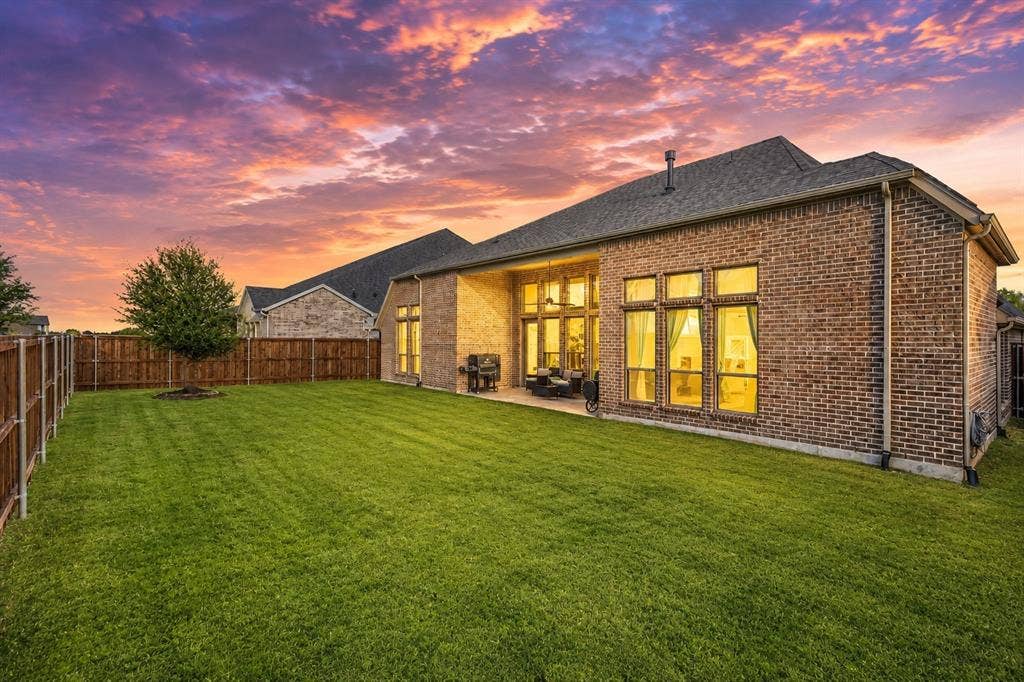 2837 Midlake Drive, Midlothian, TX 76065 Expansive green lawn with a newly planted tree, surrounded by a wood privacy fence