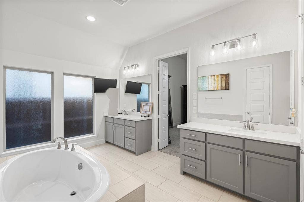 2837 Midlake Drive, Midlothian, TX 76065 Spacious bathroom featuring a built-in soaking tub, dual vanity with undermount sinks, stone countertops, and tile flooring