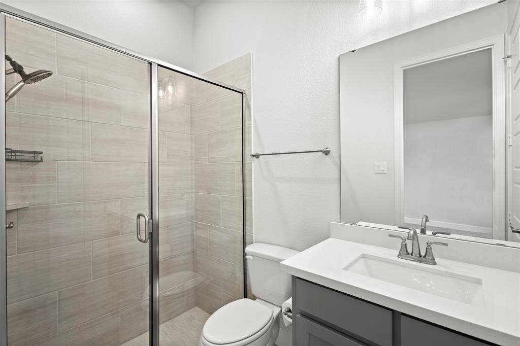 2837 Midlake Drive, Midlothian, TX 76065 Bathroom featuring a frameless glass shower enclosure with horizontal tile surround, a built-in shower niche, and a shower bench