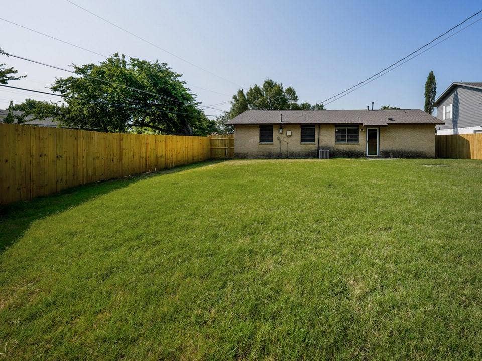 1205 Northridge Drive, Plano, TX 75075 Expansive grass lawn with a full-height wood plank privacy fence