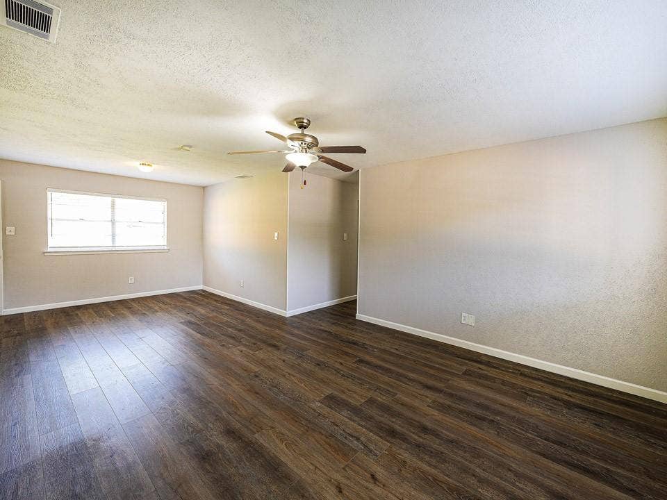 1205 Northridge Drive, Plano, TX 75075 Spacious room featuring wood-finish flooring, neutral-toned walls, a ceiling fan with integrated lighting, and a multi-pane window