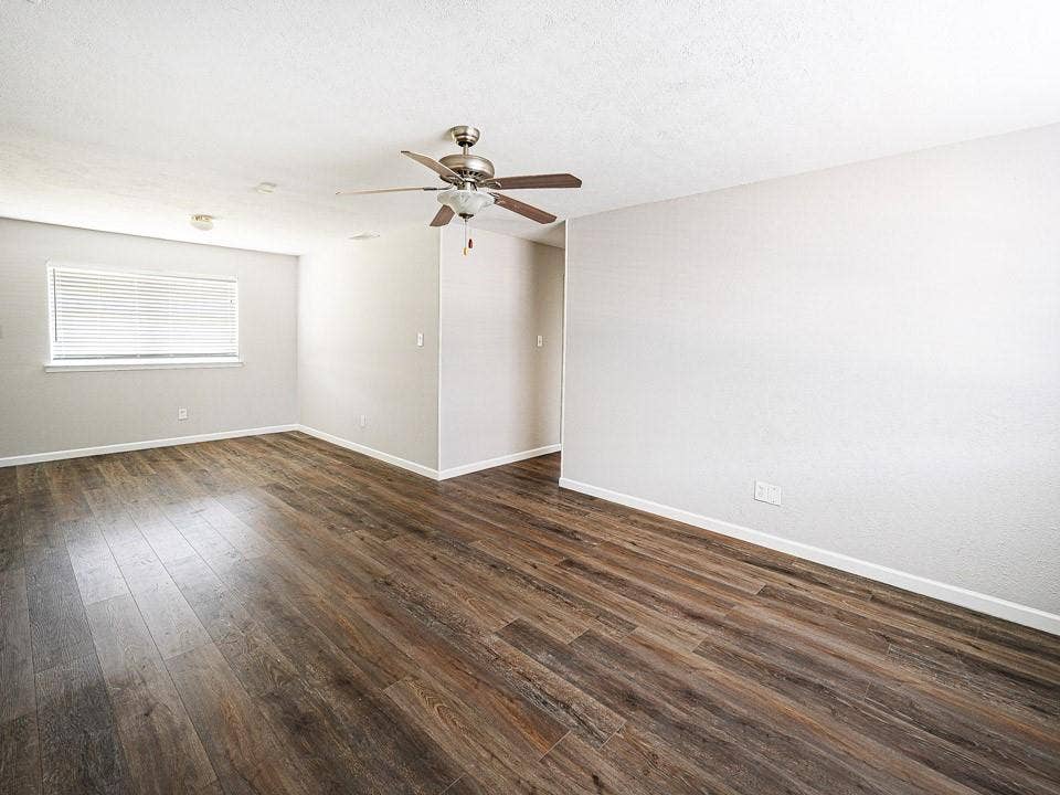 1205 Northridge Drive, Plano, TX 75075 Spacious living area showcasing wood-finish flooring throughout, neutral wall finishes, and abundant natural light from a large window