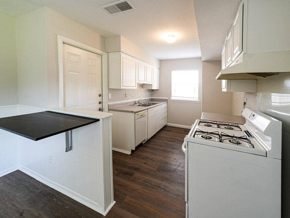 1205 Northridge Drive, Plano, TX 75075 Kitchen featuring white cabinetry, wood-finish flooring, a white gas range, a dishwasher, and a breakfast bar with a dark countertop