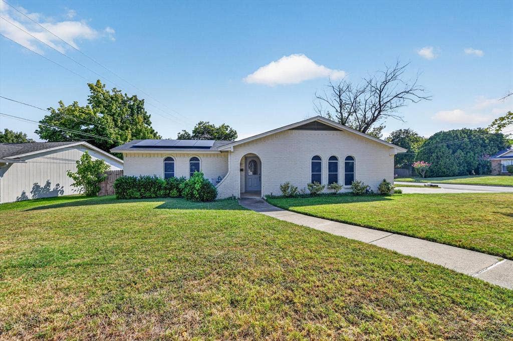 629 Newton Drive, Burleson, TX 76028 Contemporary single-story residence featuring a curved arched entryway, stucco exterior in soft cream tones, and multiple rounded windows with blue accents