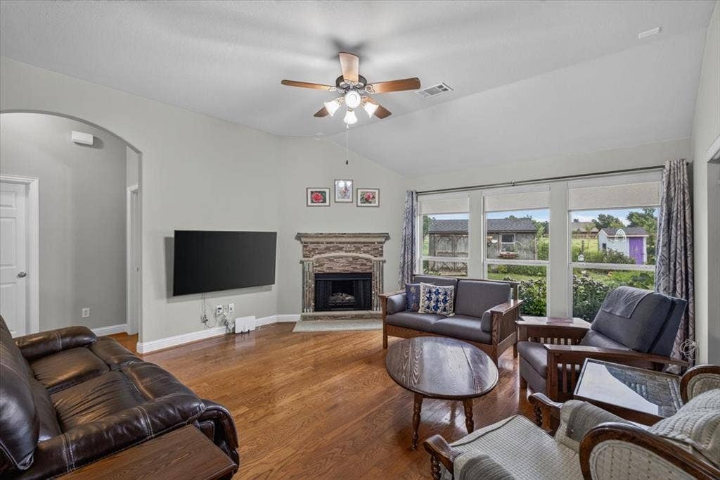 10165 Bantry Lane, Forney, TX 75126 Living room with wood flooring, a fireplace and lots of windows for natural light.