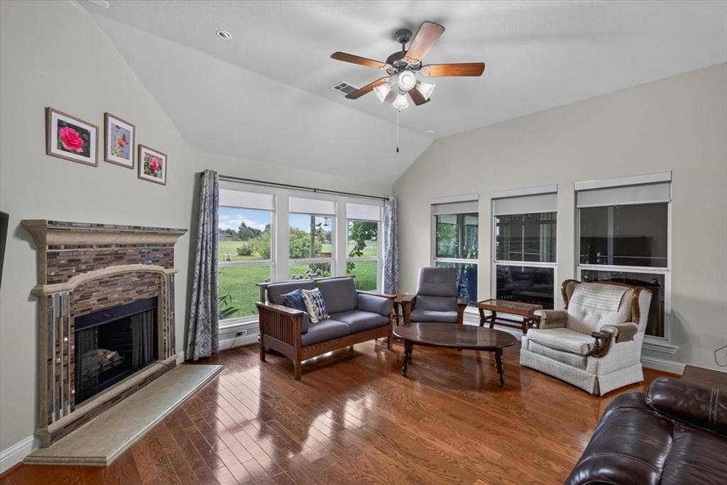 10165 Bantry Lane, Forney, TX 75126 Living room with wood flooring, a fireplace and lots of windows for natural light.