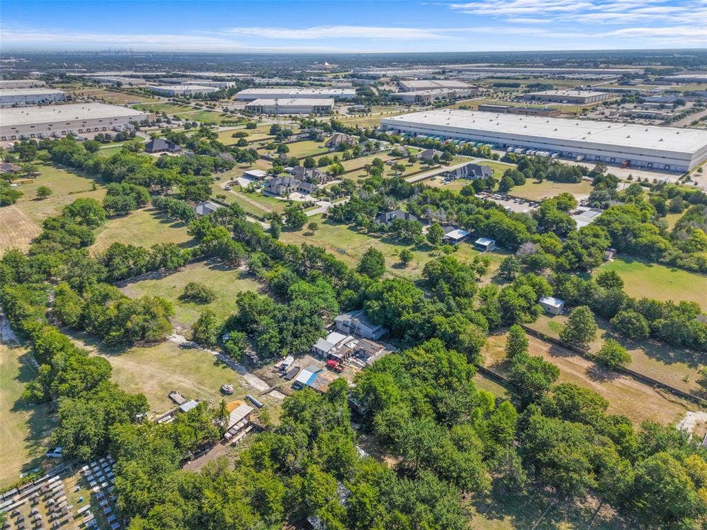 12 Winston Drive, DeSoto, TX 75115 Expansive aerial showcasing a large parcel of undeveloped land with surrounding mature trees and scattered residential properties
