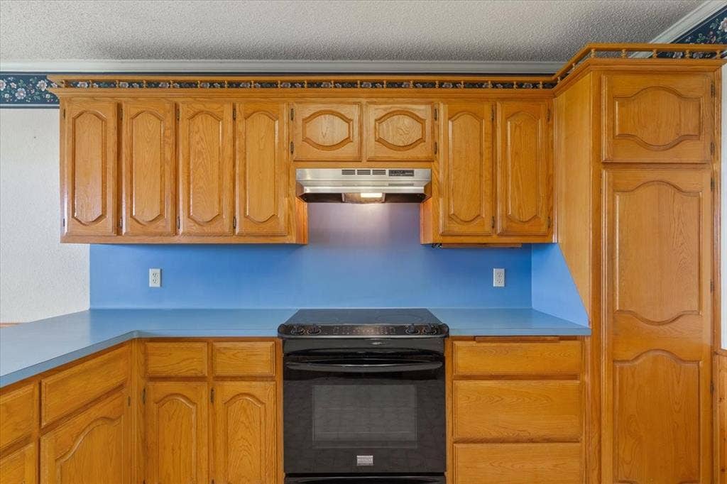 146 Indian Paint Brush Road, Eddy, TX 76524 Kitchen featuring wood cabinetry, blue countertops, and a black range with an overhead vent hood