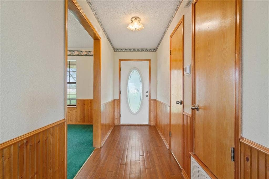 146 Indian Paint Brush Road, Eddy, TX 76524 Entryway featuring wood-finish flooring, paneled wainscoting, and a white front door with an oval-shaped opaque glass insert