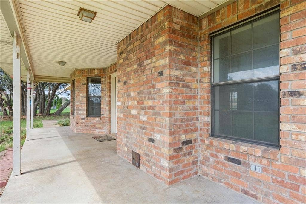 146 Indian Paint Brush Road, Eddy, TX 76524 Brick exterior featuring a covered concrete porch, white column supports, and a vinyl soffit ceiling with two flush-mount light fixtures