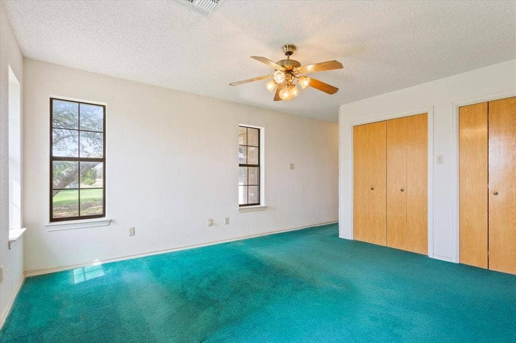 146 Indian Paint Brush Road, Eddy, TX 76524 Spacious room featuring two windows with exterior views, bright white walls, and a ceiling fan with integrated lighting