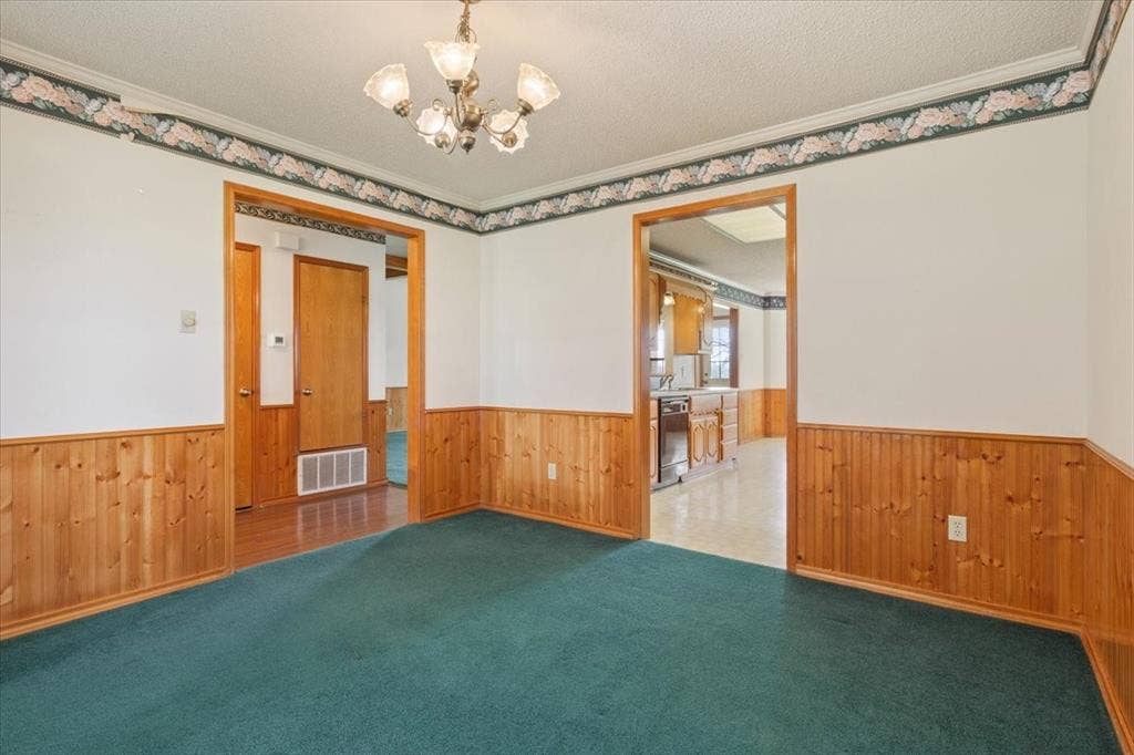 146 Indian Paint Brush Road, Eddy, TX 76524 Interior room featuring wainscoting, green carpet, and a decorative chandelier