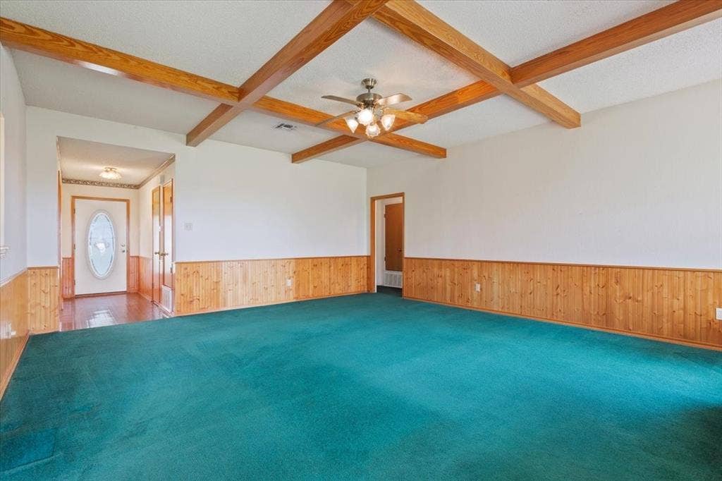 146 Indian Paint Brush Road, Eddy, TX 76524 Spacious room featuring exposed wood ceiling beams, a ceiling fan with integrated lighting, and wood-paneled wainscoting