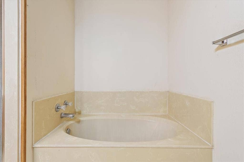 146 Indian Paint Brush Road, Eddy, TX 76524 Built-in corner soaking tub with deck-mounted faucet and clear acrylic handles, set within a light-toned surround