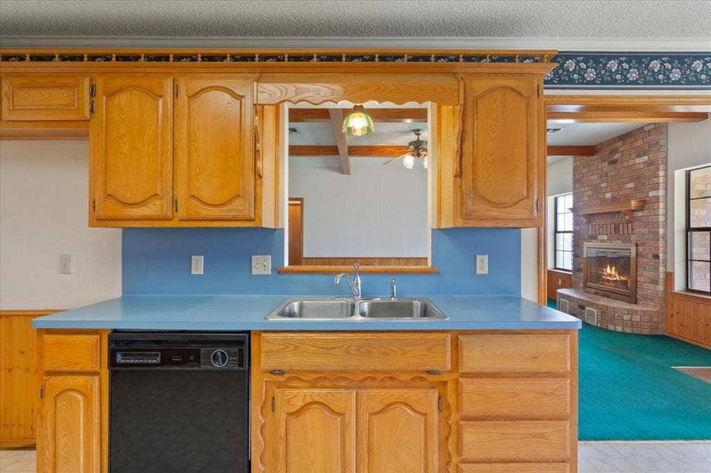 146 Indian Paint Brush Road, Eddy, TX 76524 Kitchen featuring wood cabinetry, a double basin stainless steel sink, a black dishwasher, and a blue countertop