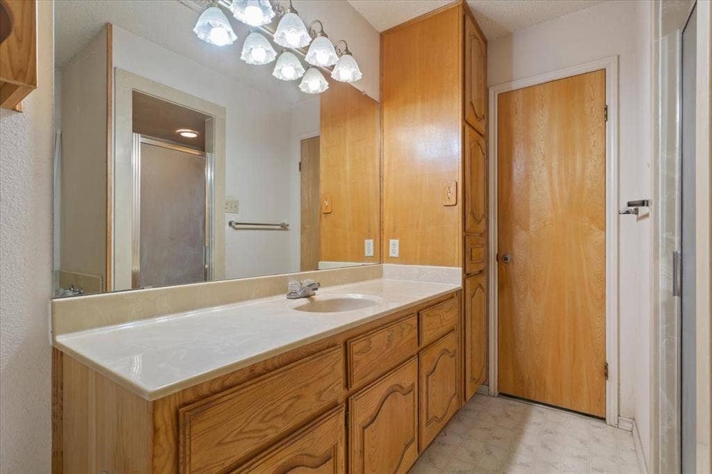 146 Indian Paint Brush Road, Eddy, TX 76524 Bathroom vanity featuring a light-toned countertop, integrated sink, and an extensive wood-finish cabinet with multiple drawers and doors