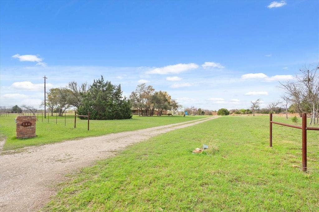 146 Indian Paint Brush Road, Eddy, TX 76524 Expansive green lawn with a long gravel driveway