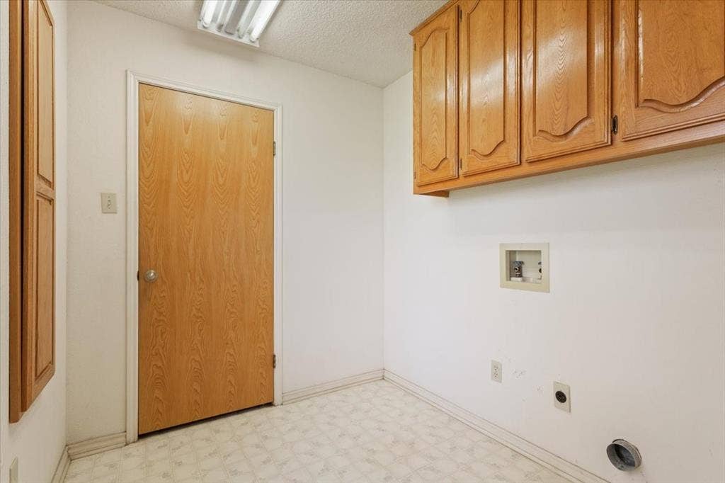 146 Indian Paint Brush Road, Eddy, TX 76524 Laundry area with light wood-finish cabinetry, patterned vinyl flooring, and a flush-mount fluorescent light fixture