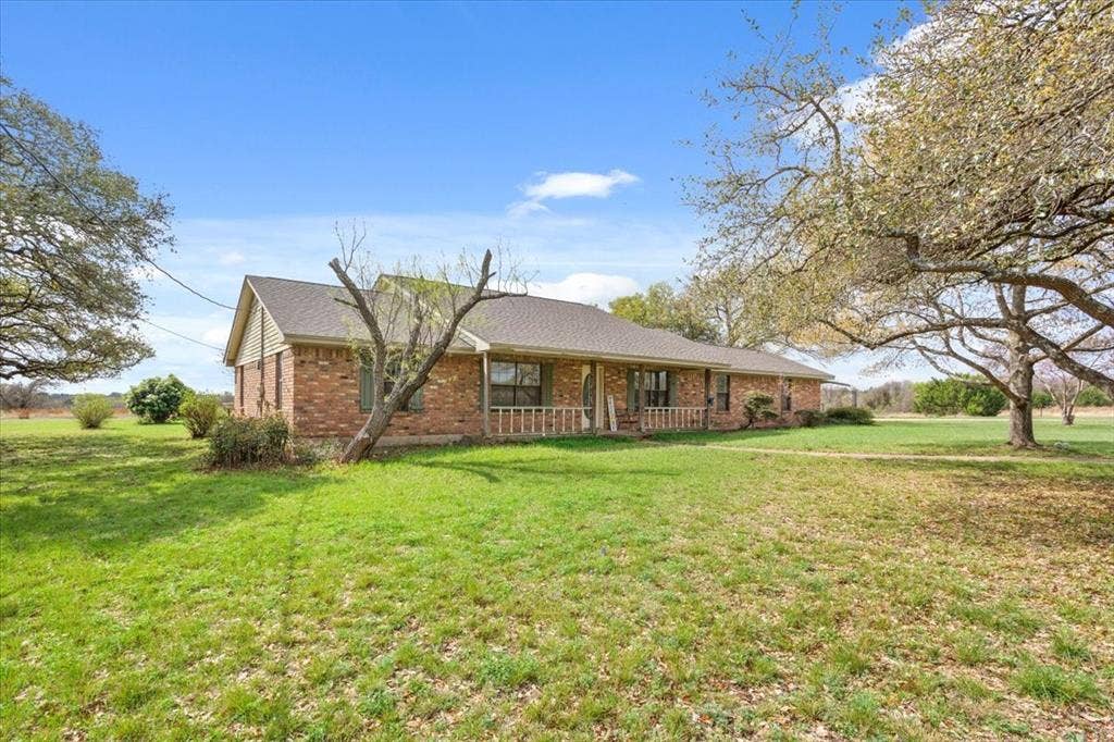 146 Indian Paint Brush Road, Eddy, TX 76524 Brick facade residence with a gabled roofline, a covered front porch, and a lush green lawn