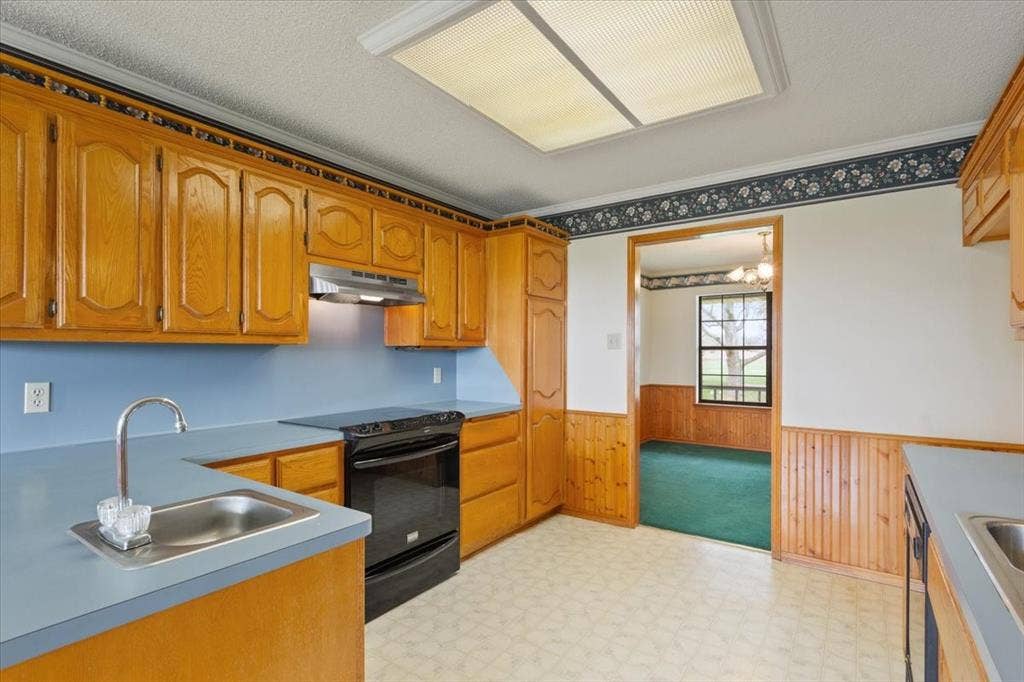 146 Indian Paint Brush Road, Eddy, TX 76524 Kitchen featuring wood cabinetry, a stainless steel sink, black range, and a light blue backsplash