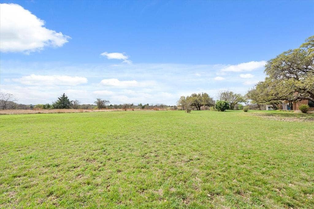 146 Indian Paint Brush Road, Eddy, TX 76524 Expansive green field featuring a partially visible brick structure and mature trees