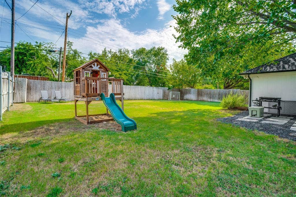 8201 Christie Drive, Frisco, TX 75033 Expansive backyard featuring a lush lawn, wooden privacy fencing, mature trees, and a dedicated patio area with paver stones and decorative gravel
