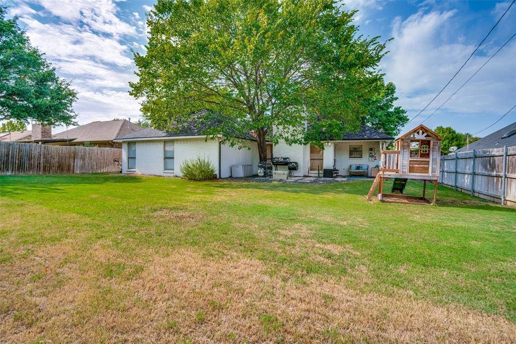 8201 Christie Drive, Frisco, TX 75033 Expansive backyard featuring a manicured lawn, mature trees, and privacy fencing