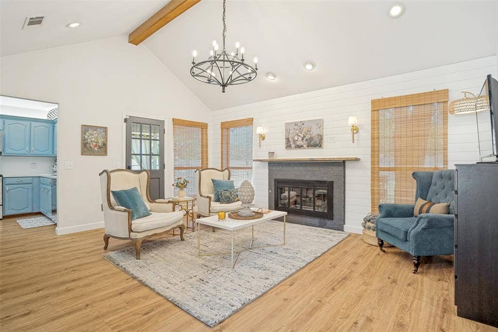 8201 Christie Drive, Frisco, TX 75033 Vaulted ceiling with exposed wood beam, wood-finish flooring, and a modern fireplace with a dark surround and wood mantel