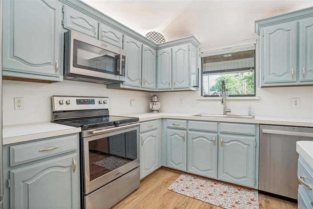 8201 Christie Drive, Frisco, TX 75033 Kitchen featuring light blue cabinetry with gold-toned hardware, white countertops, and wood-finish flooring