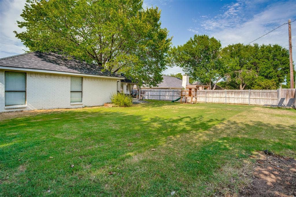 8201 Christie Drive, Frisco, TX 75033 Spacious backyard with a wooden privacy fence, mature trees, and a substantial grassy area