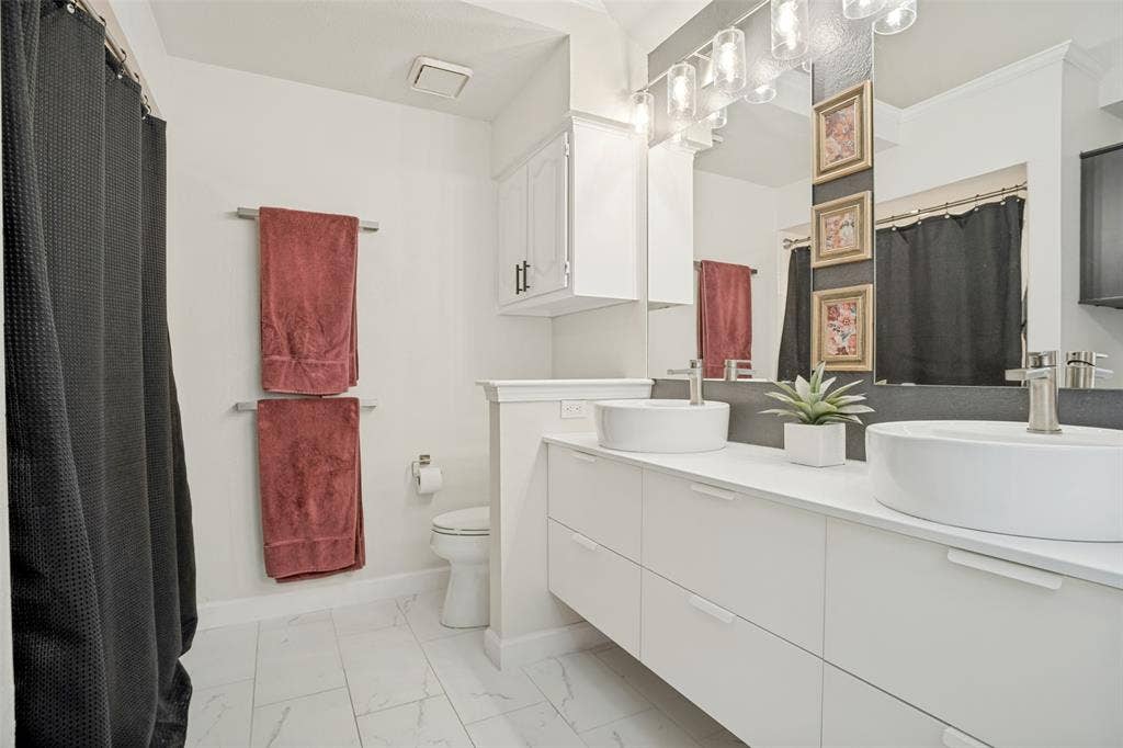 8201 Christie Drive, Frisco, TX 75033 Spacious bath featuring dual vessel sinks, white cabinetry, a large mirror, chrome fixtures, and tile flooring
