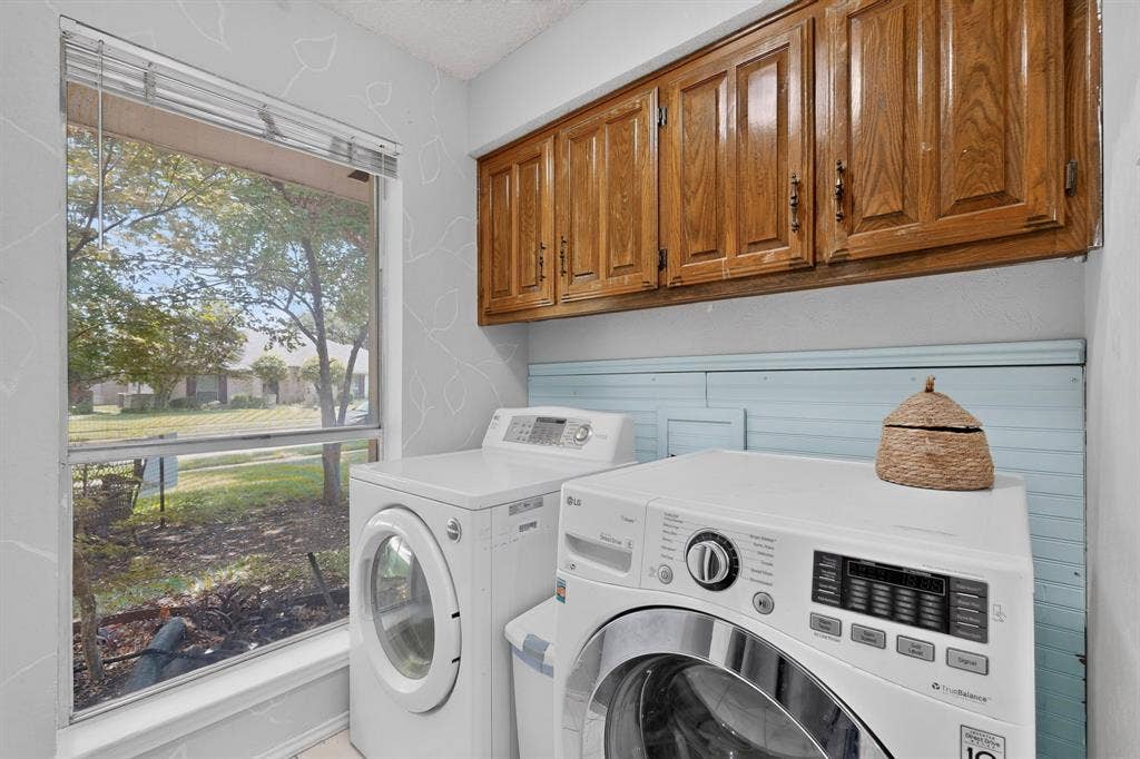 2003 J J Pearce Drive, Richardson, TX 75081 Laundry area featuring wood cabinetry, light blue wainscoting, and a large window overlooking green space