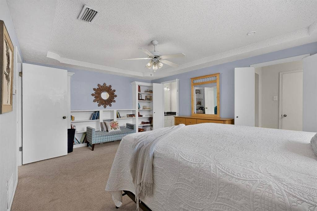2003 J J Pearce Drive, Richardson, TX 75081 Bedroom featuring built-in shelving, tray ceiling, ceiling fan, and carpeted flooring
