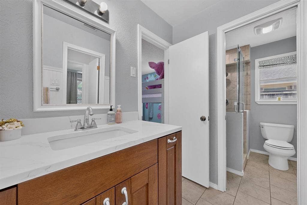 2003 J J Pearce Drive, Richardson, TX 75081 Bathroom vanity featuring a white countertop with an integrated sink, chrome faucet, and wood-finish cabinetry